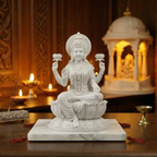 White marble statue of a seated figure with lotus pedestal on a wooden table, candles and incense in the background.