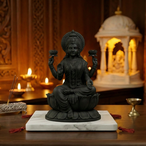 Black statue of a seated figure on a marble base with candles and incense in a decorative setting.